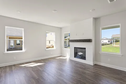 an empty room with wooden floor fireplace and windows