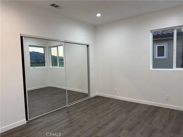 an empty room with wooden floor and mirror