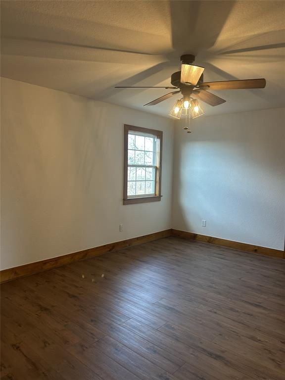 307 County Road 4790 Boyd, TX 76023 - Photo 12 of 25 an empty room with wooden floor chandelier fan and windows