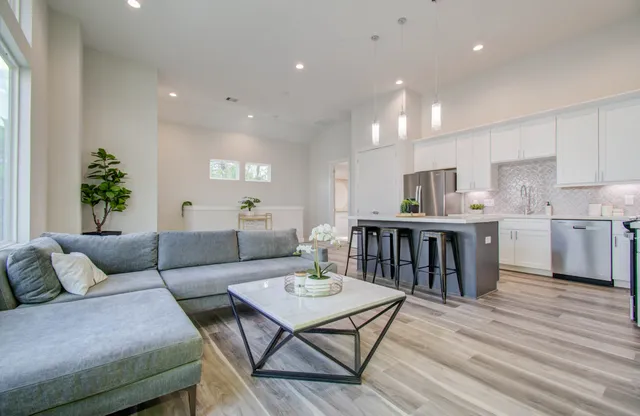 a living room filled with furniture and kitchen view