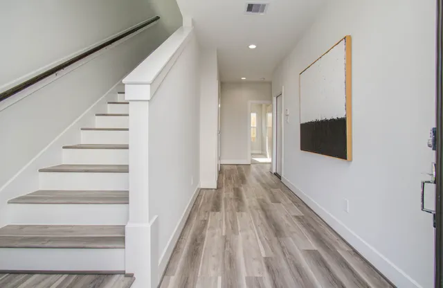 a view of a hallway with wooden floor and staircase