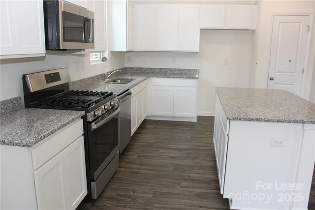 a kitchen with granite countertop wooden cabinets and white appliances