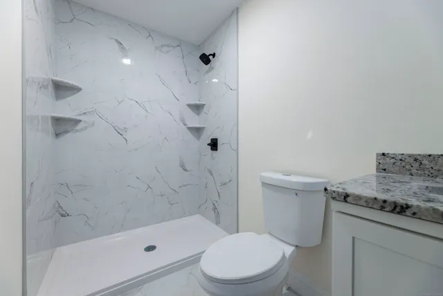 a bathroom with a granite countertop sink toilet and shower