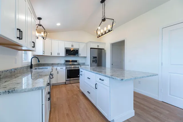 a kitchen with stainless steel appliances granite countertop a sink a stove and a refrigerator