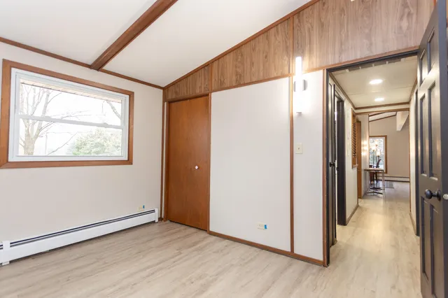 a view of a hallway with wooden floor and cabinet