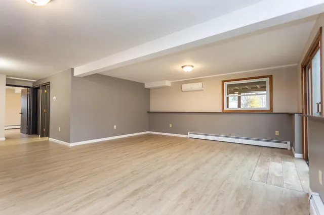 a view of an empty room with window and wooden floor