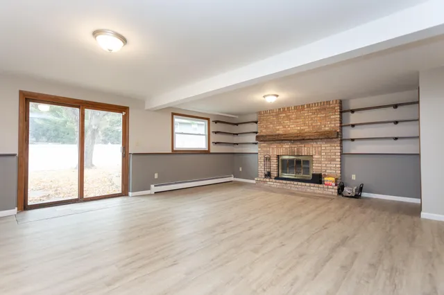 an empty room with windows and fireplace