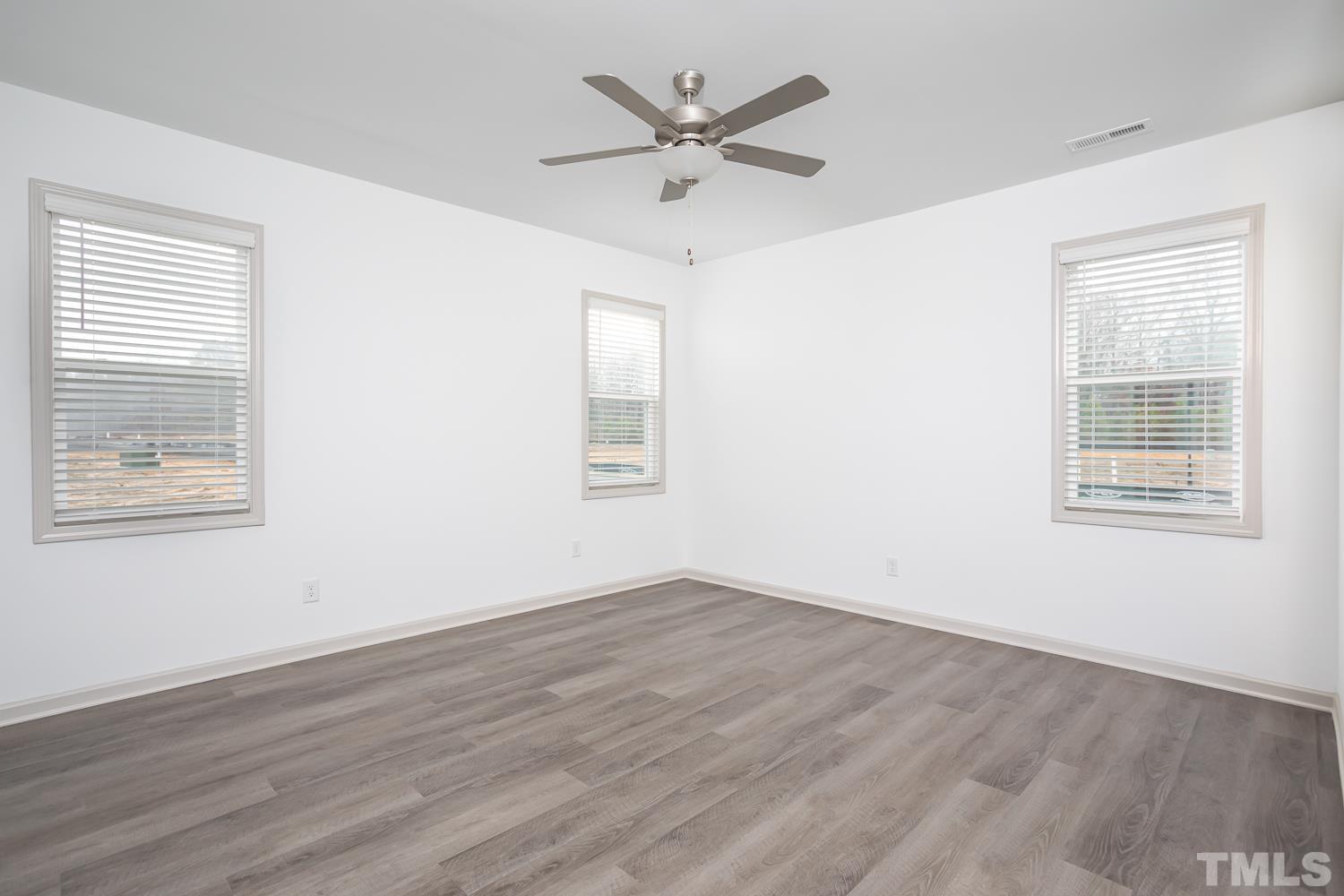 749 Hadstock Path Zebulon, NC 27597 - Photo 14 of 25 an empty room with wooden floor chandelier fan and windows