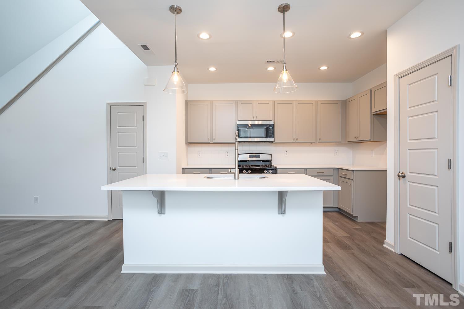 749 Hadstock Path Zebulon, NC 27597 - Photo 4 of 25 a kitchen with kitchen island a sink stainless steel appliances and cabinets
