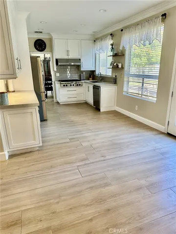 a kitchen with a sink wooden floor and stainless steel appliances