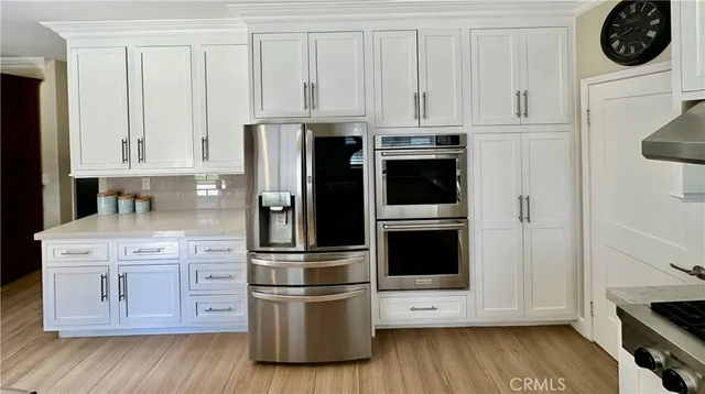 a kitchen with stainless steel appliances white cabinets and a refrigerator