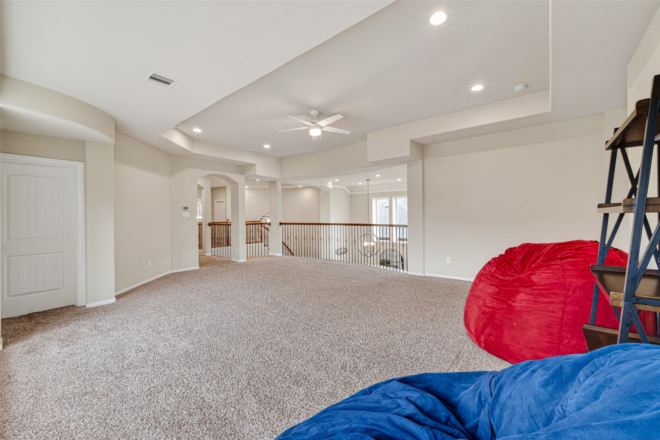 25611 Ellis Ridge Court Katy, TX 77494 - Photo 23 of 49 This spacious, carpeted loft area features neutral walls, recessed lighting, and a ceiling fan. It includes a stylish open railing overlooking a lower level, with ample natural light from large windows. Ideal for a family room or entertainment space.