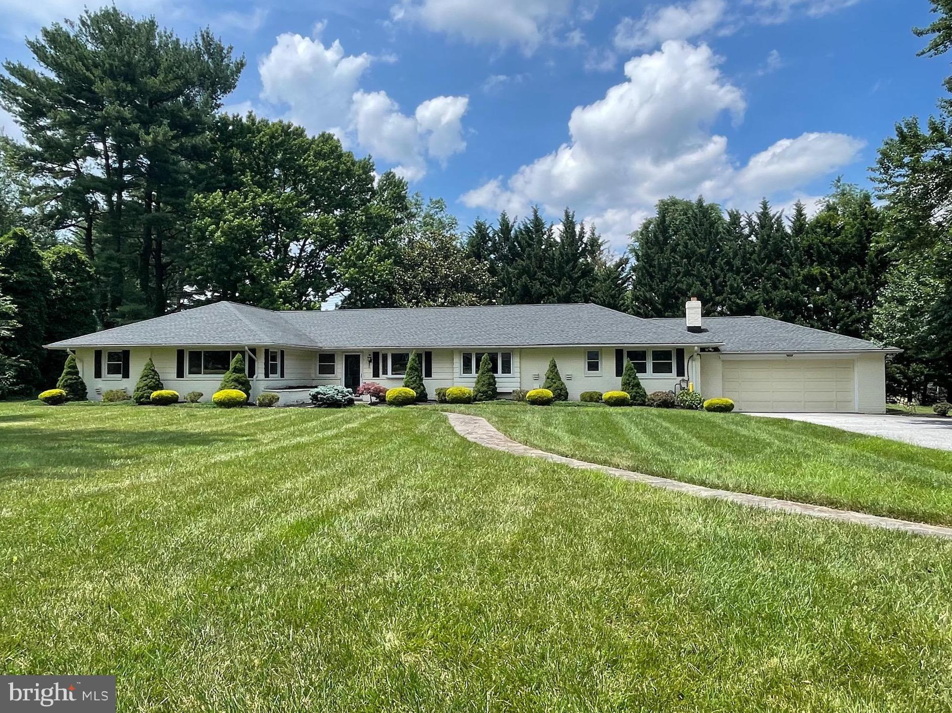 a view of a house with a big yard and large trees