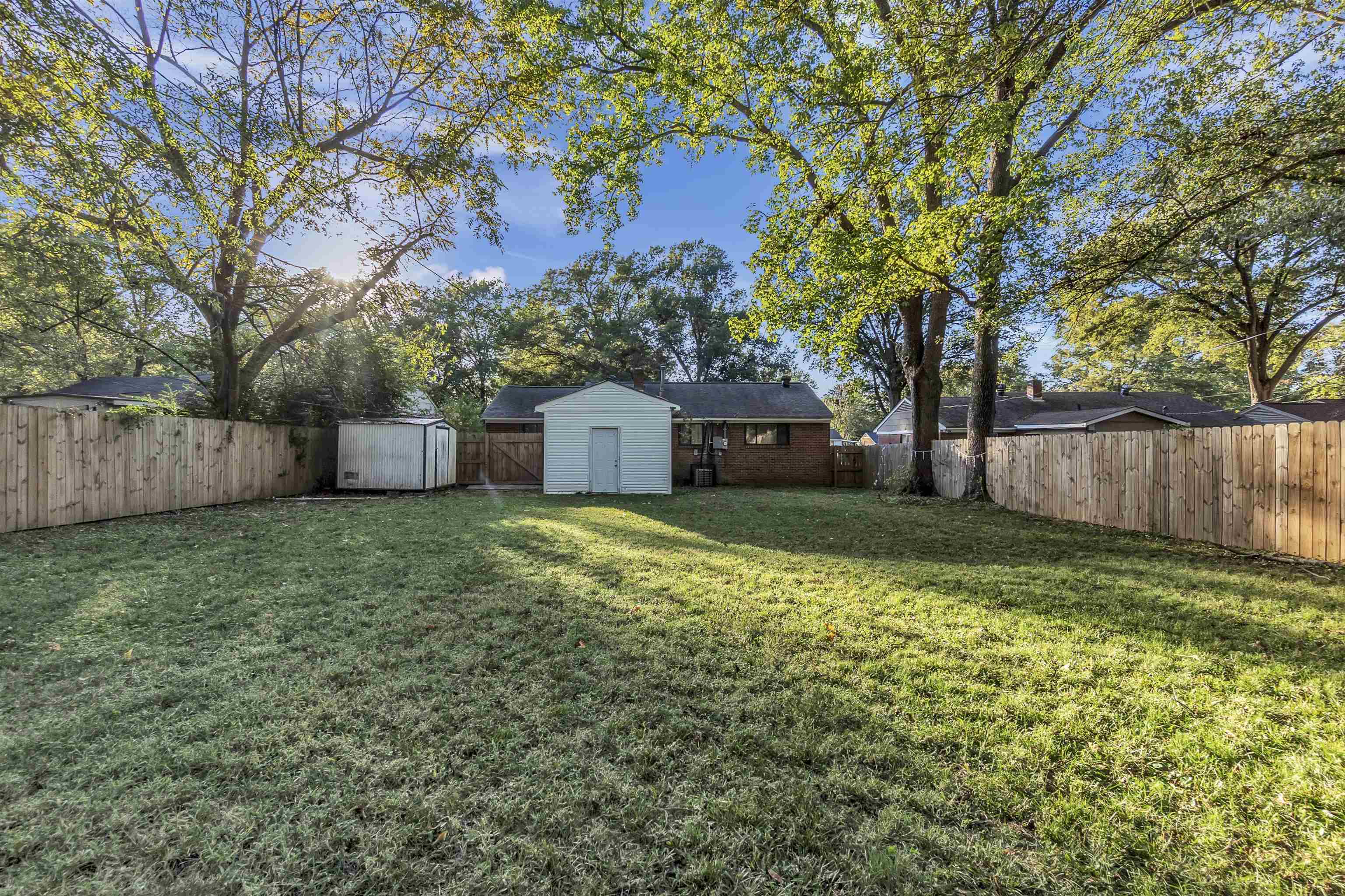1136 South White Station Road Memphis, TN 38117 - Photo 18 of 19 a view of a backyard with large trees and wooden fence