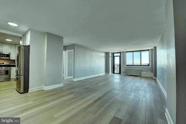 a view of an empty room with window and wooden floor