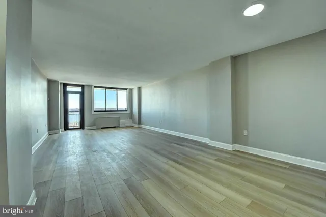 a view of an empty room with window and wooden floor