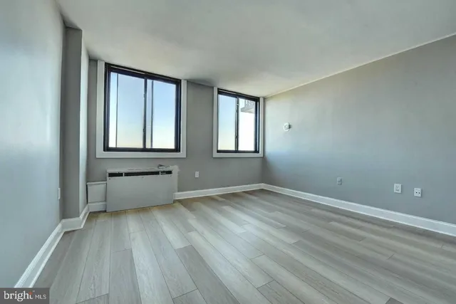 an empty room with wooden floor and windows