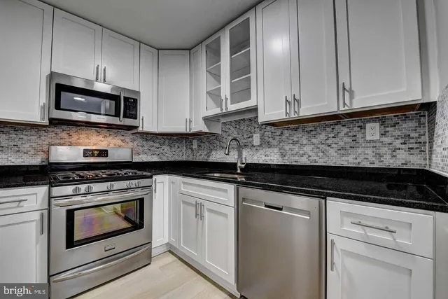 a kitchen with white cabinets and stainless steel appliances