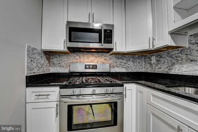 a kitchen with stainless steel appliances granite countertop white cabinets granite counter tops and a wooden floors