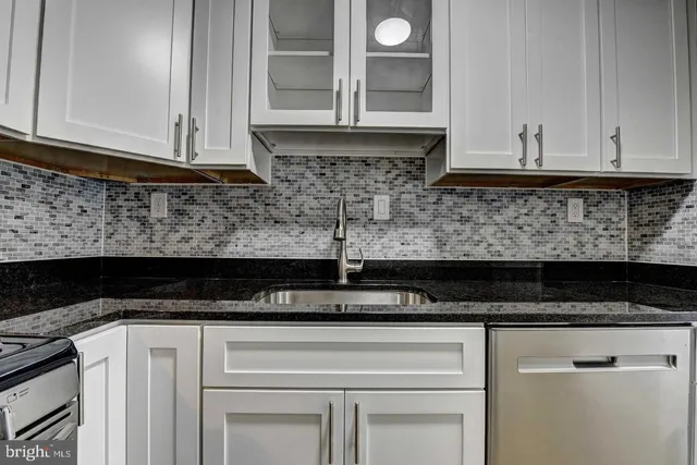 a kitchen with white cabinets and sink
