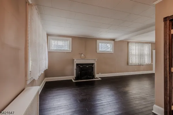 an empty room with wooden floor fireplace and windows