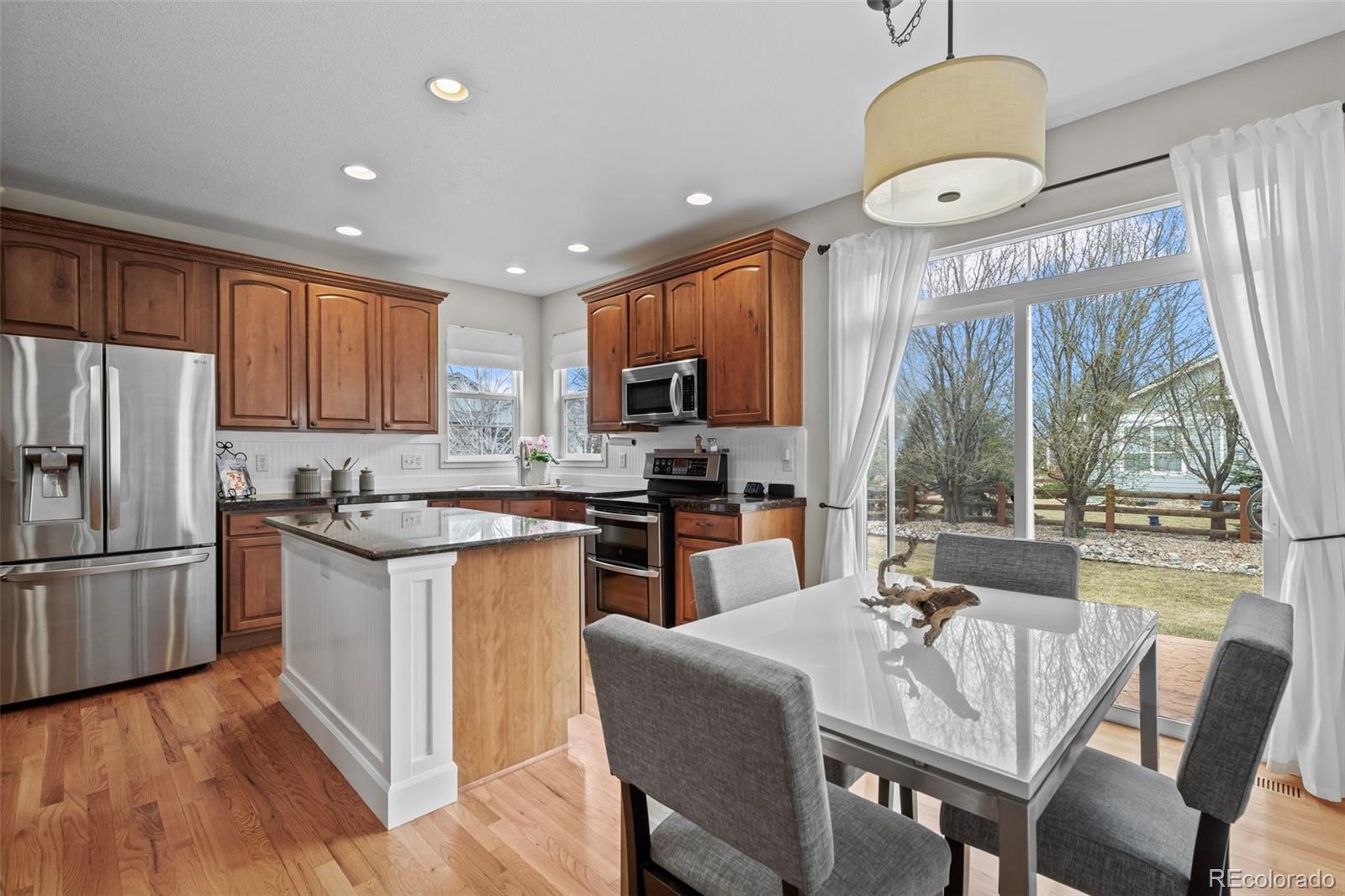 4463 Eagle River Run Broomfield, CO 80023 - Photo 12 of 44 a kitchen with stainless steel appliances granite countertop a stove top oven a refrigerator a sink and a dining table with garden view