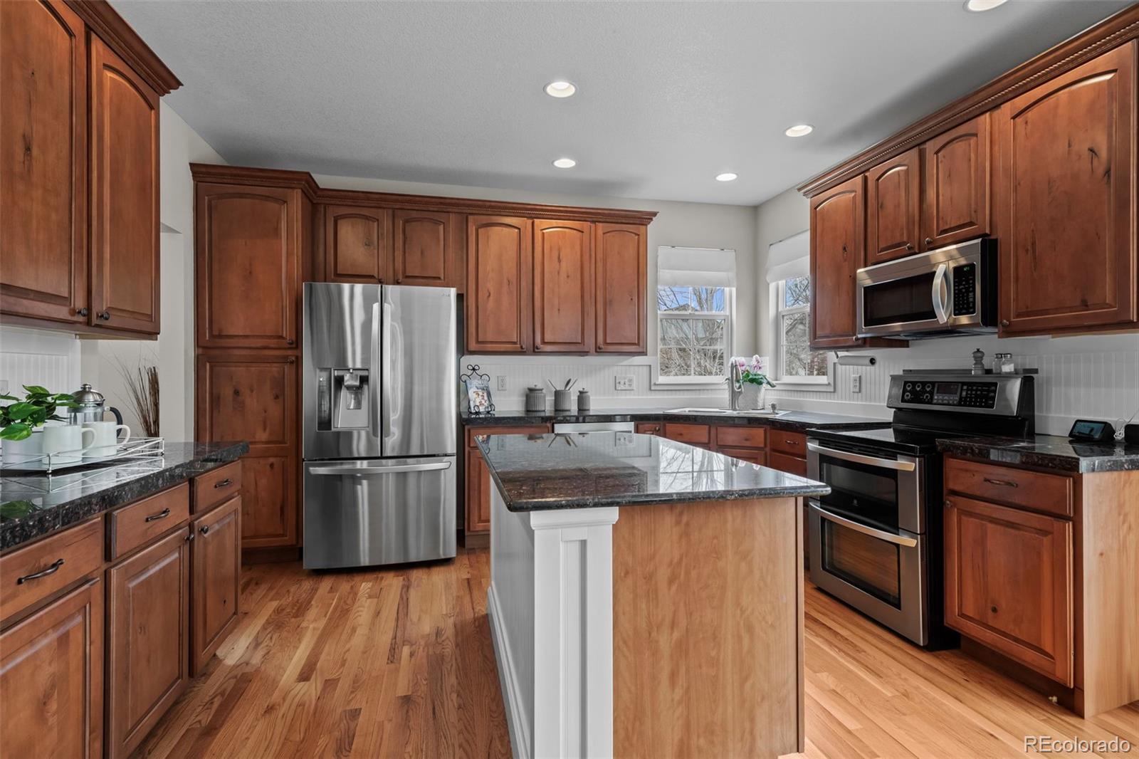 4463 Eagle River Run Broomfield, CO 80023 - Photo 13 of 44 a kitchen with stainless steel appliances granite countertop a refrigerator a stove top oven a sink and dishwasher with wooden floor