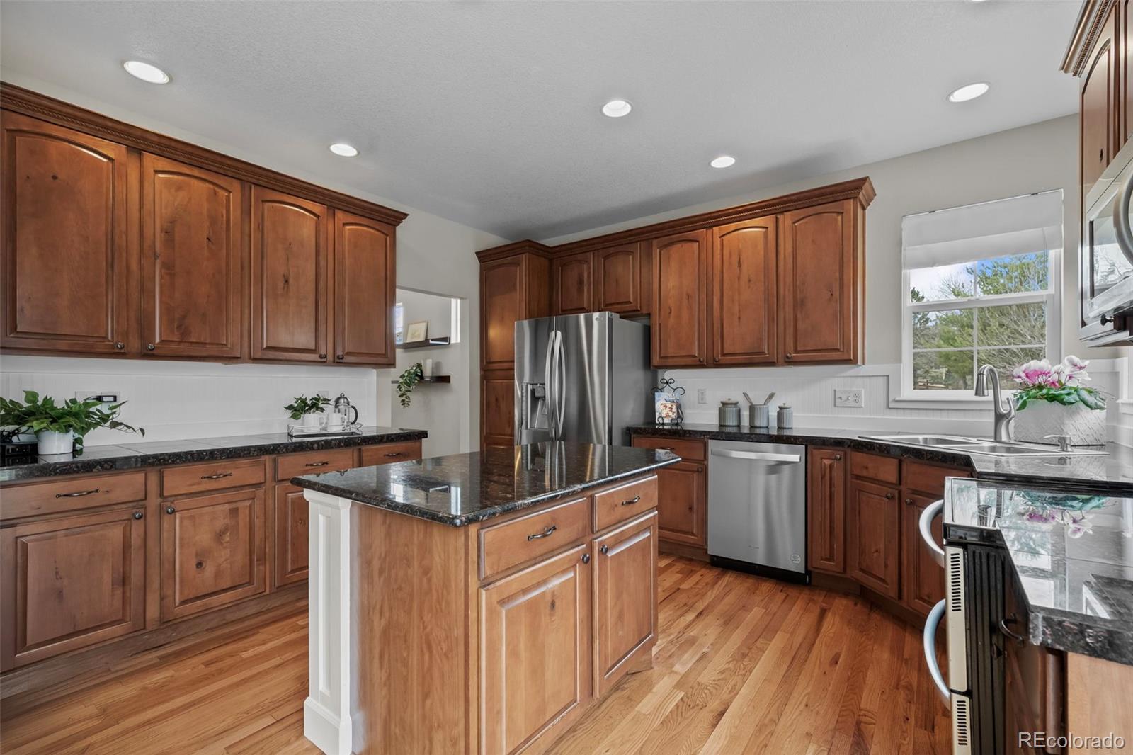 4463 Eagle River Run Broomfield, CO 80023 - Photo 14 of 44 a kitchen with granite countertop wooden cabinets stainless steel appliances a window and a center island