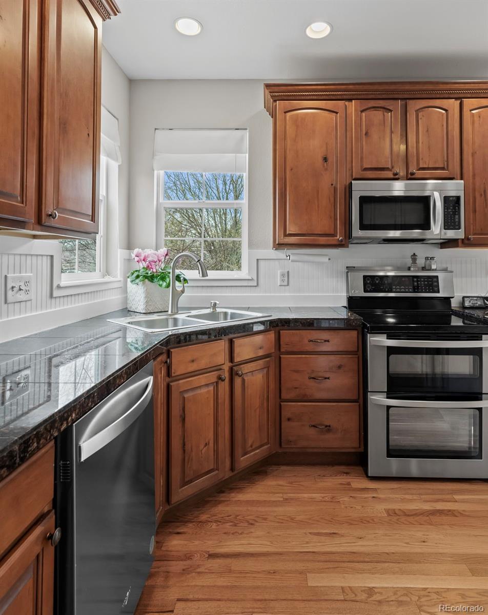 4463 Eagle River Run Broomfield, CO 80023 - Photo 16 of 44 a kitchen with stainless steel appliances granite countertop a stove a sink and a microwave