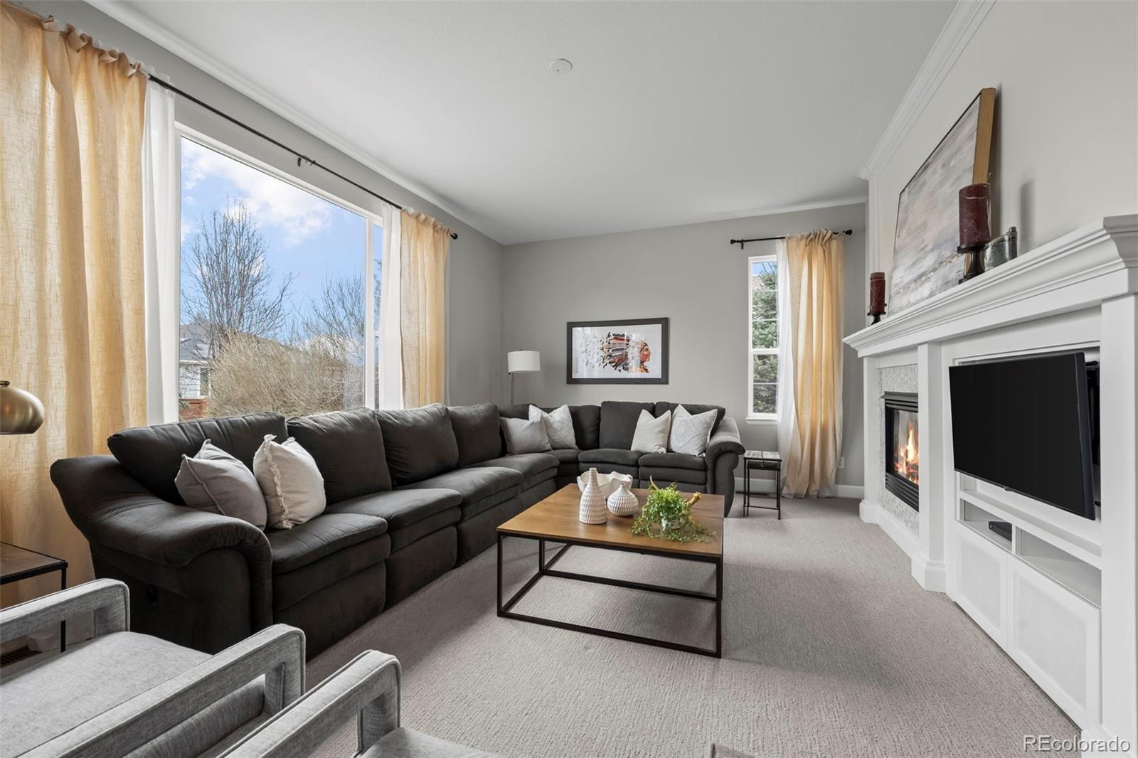 4463 Eagle River Run Broomfield, CO 80023 - Photo 18 of 44 a living room with furniture a flat screen tv and a fireplace