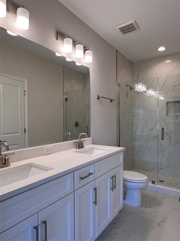 7741 93rd Street North Seminole, FL 33777 - Photo 9 of 11 a bathroom with a double vanity sink toilet and a mirror