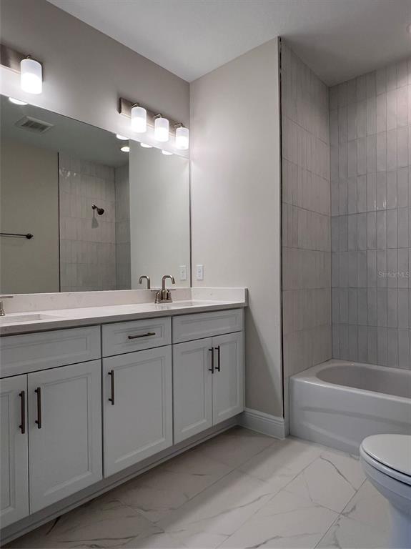 7741 93rd Street North Seminole, FL 33777 - Photo 10 of 11 a bathroom with a double vanity sink toilet and shower