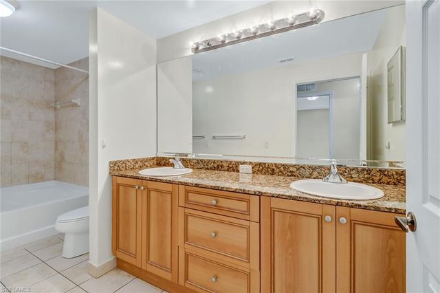 a bathroom with a granite countertop sink a toilet a mirror and bathtub