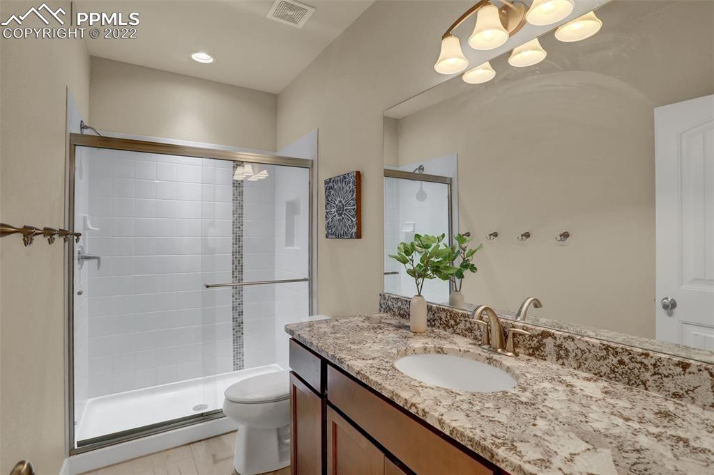 1435 Catnap Lane Monument, CO 80132 - Photo 38 of 47 a bathroom with a granite countertop sink a toilet and shower
