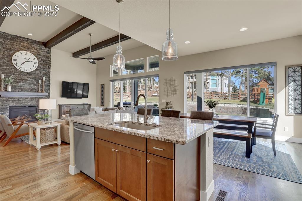 1435 Catnap Lane Monument, CO 80132 - Photo 8 of 47 a kitchen with a stove a sink dishwasher a dining table and chairs with wooden floor