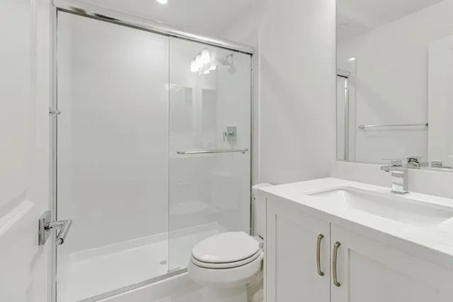 a bathroom with a shower sink vanity mirror and toilet