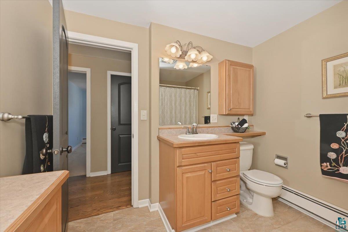 1918 West Kent Road Duluth, MN 55812 - Photo 16 of 42 Bathroom featuring a light wood-finish vanity with an integrated sink, coordinating wall cabinet, and a mirror with decorative lighting