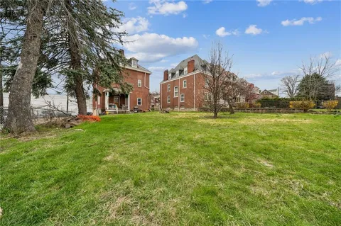 a view of a building with a big yard and large trees