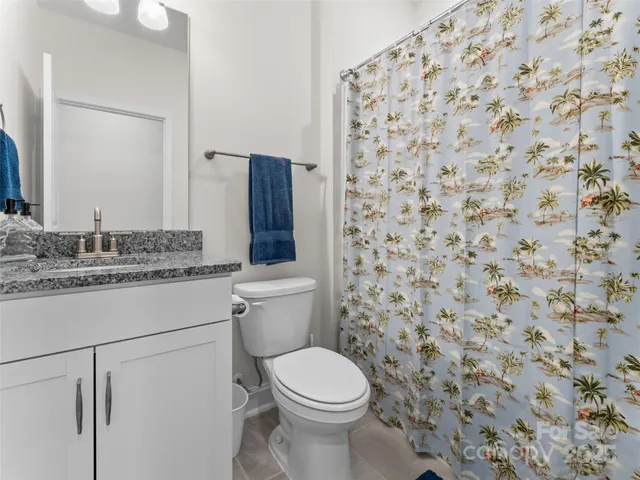 a bathroom with a granite countertop toilet and a sink