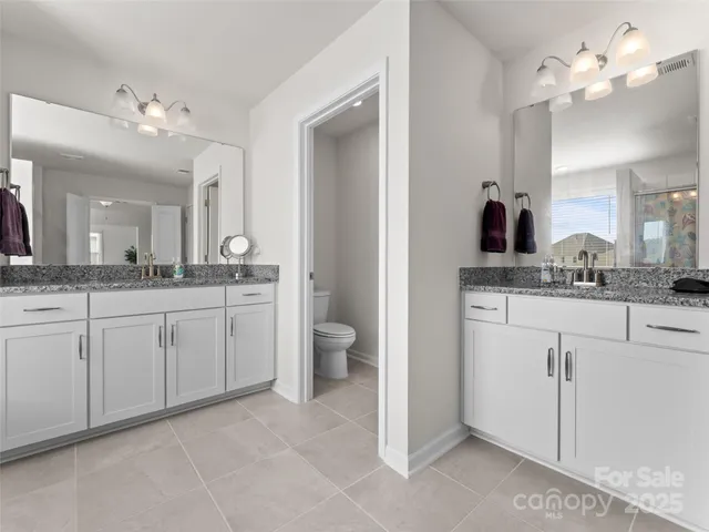 a spacious bathroom with a granite countertop sink a toilet and a mirror