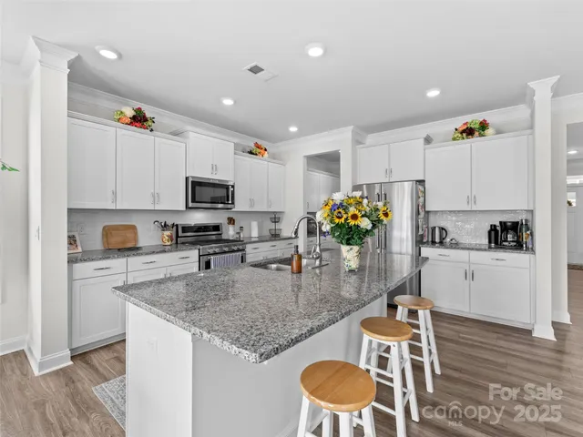 a kitchen with granite countertop kitchen island stainless steel appliances a stove a sink a microwave a refrigerator and cabinets