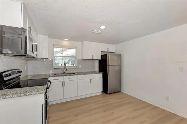 a kitchen with granite countertop a sink stove and refrigerator