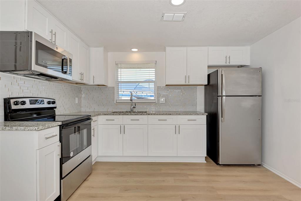 1601 Faust Drive, Unit B Englewood, FL 34224 - Photo 4 of 19 a kitchen with stainless steel appliances granite countertop a refrigerator stove a sink and a microwave