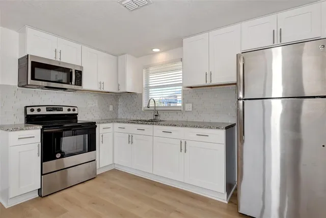 a kitchen with stainless steel appliances white cabinets and a refrigerator