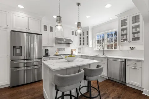 a kitchen with stainless steel appliances granite countertop a sink a stove a refrigerator and island with wooden floor