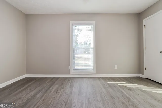 a view of an empty room with wooden floor and a window
