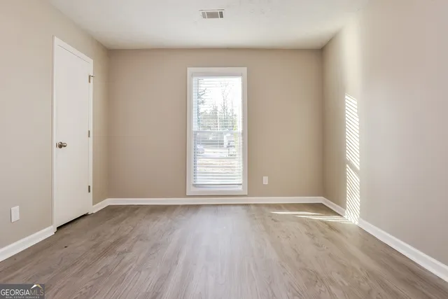 an empty room with wooden floor and windows
