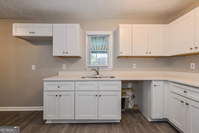 a kitchen with white cabinets and sink