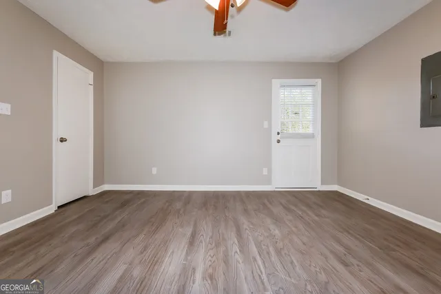 an empty room with wooden floor cabinet and windows