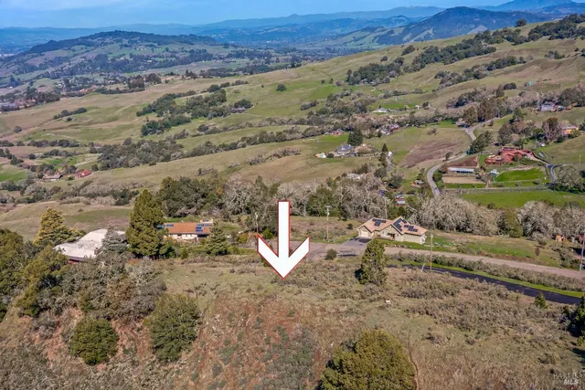an aerial view of a house with a yard and mountain view